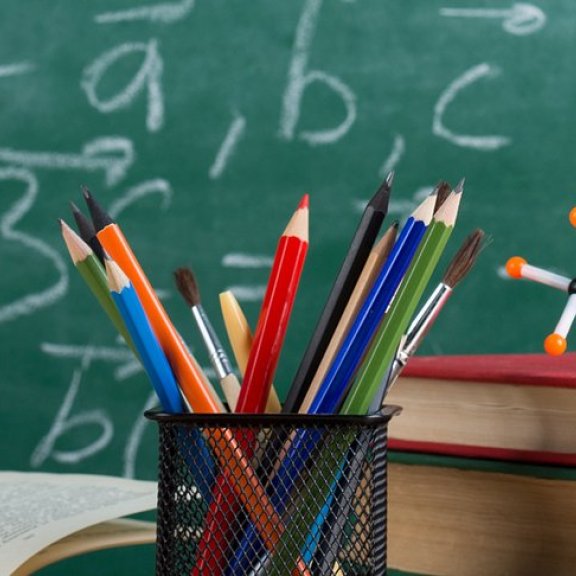 Buntstifte, Bücherstapel und Molekül-Modell vor Kreidetafel mit Vektorrechnung