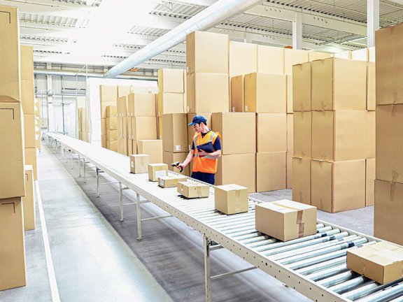 Ein Mann bearbeitet eingehende Paketlieferungen in einem großen Lagerraum