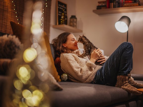 Eine Frau kuschelt mit ihrer Katze auf dem Sofa.